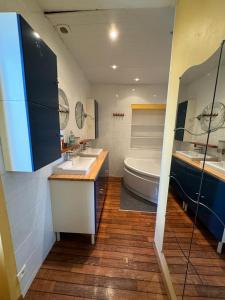 uma casa de banho com 2 lavatórios, uma banheira e um WC. em La Bourgeoise em Neuvic