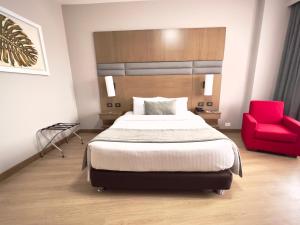 a bedroom with a bed and a red chair at Hotel Dann Carlton Cali in Cali