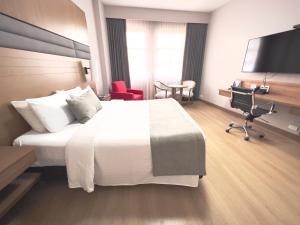 a hotel room with a large bed and a desk at Hotel Dann Carlton Cali in Cali