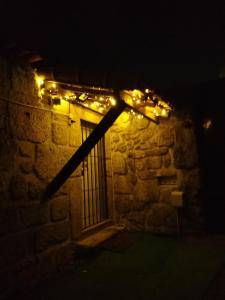 un mur en pierre avec quelques lumières sur lui dans l'établissement Casa da Aldeia, à Vilela