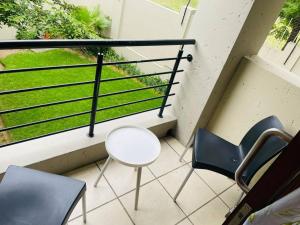 a balcony with two chairs and a white table and chairs at 361 On Sunset in Sandton