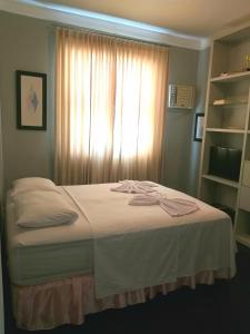 a bedroom with a bed with white sheets and a window at Erva Cidreira Hostel in Salvador