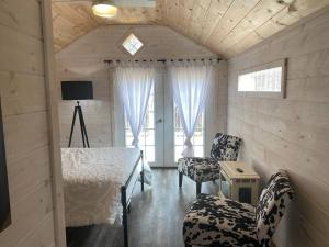 een slaapkamer met een bed en 2 stoelen in een kamer bij Cottage Core Farmstay @ the TINY HOME in Trenton