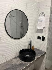 baño con lavabo negro y espejo en Hotel Celeste Inn Chinauta- Fusagasugá, en Chinauta