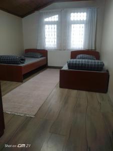 two beds in a room with wooden floors and windows at Rooftop apartment with a big garden in Kocaeli
