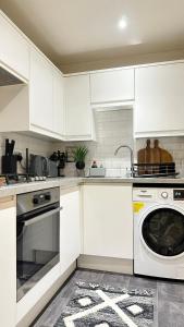 una cucina con armadietti bianchi e lavastoviglie di Superb & Stylish - Gated Community - Free Parking a Hatfield