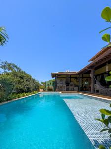 a swimming pool with blue water in front of a house at Reduto do Alto in Búzios