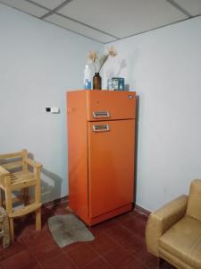 an orange refrigerator in a room with a chair at CASA EN TAFI DEL VALLE ZONA LA ANGOSTURA in San Miguel de Tucumán