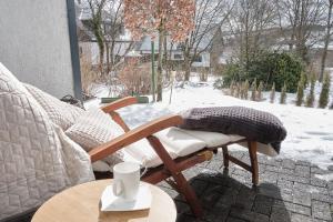 a chair on a patio with snow on the ground at MILANA Naturpanorma, ruhig & familienfreundlich in Winterberg