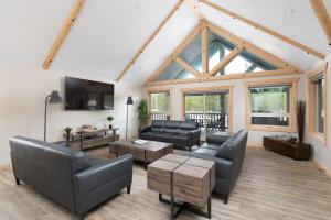 a living room with leather furniture and a large window at Lazy Moose in Valemount