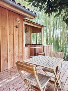 einen Holztisch und Stühle auf einer Holzterrasse in der Unterkunft maisonette et spa bois in La Bégude-de-Mazenc
