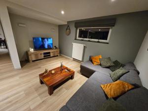 - un salon avec un canapé et une télévision dans l'établissement Les Secrets du Bois, à Vielsalm