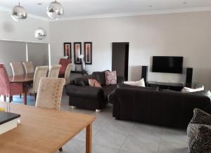 a living room with a black couch and a table at Missie Villa 165 on Rooibok Euphoria Golf in Naboomspruit