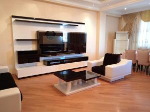 a living room with a large television and white furniture at Kvartira in Baku