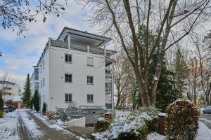 un immeuble d'appartements blanc avec de la neige au sol dans l'établissement apanoxa homes I zentral I Parkplätze I Deluxe Apartment, à Straubing