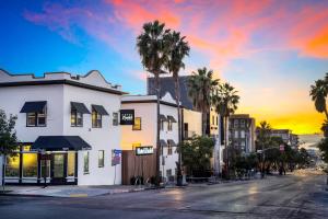 a city street with buildings and palm trees at sunset at Hotel Zindel in San Diego
