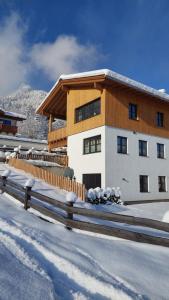 Ein Gebäude mit einem Zaun im Schnee in der Unterkunft Ferienwohnung Ida in Lofer