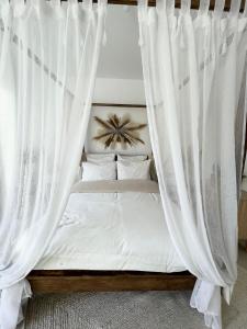 un letto con tende bianche in una camera da letto di La Gabriela a Tournon-sur-Rhône
