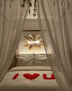 un letto con tende bianche e fiori rossi sopra di La Gabriela a Tournon-sur-Rhône