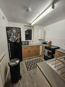 a kitchen with a black refrigerator with magnets on it at Stunning 1-Bed Apartment in London in London