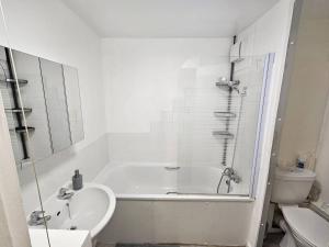 uma casa de banho com uma banheira, um lavatório e um WC. em Stunning 1-Bed Apartment in London em Londres