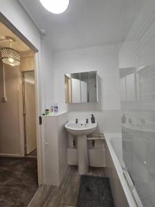 a white bathroom with a sink and a bath tub at Stunning 1-Bed Apartment in London in London