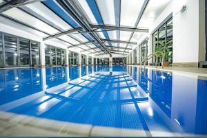 an indoor swimming pool with blue tile floors and windows at Crystal Loft Apartment 212 in Bakuriani