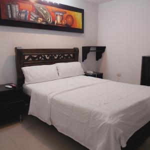 a bedroom with a large bed with white sheets at HOTEL SARACHUY VALLEDUPAR in Valledupar