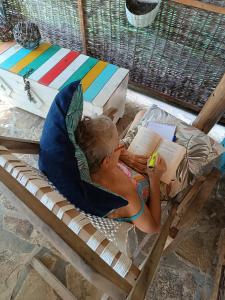 un enfant dormant dans un lit en lisant un livre dans l'établissement Cabañas Puesta del Sol, à Las Peñitas
