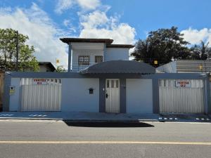 マナウスにあるHotel Residencial Manaus - Floresの二つのガレージドアと通りを持つ白い建物