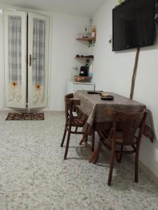 een eetkamer met een tafel en stoelen en een televisie bij Camera Brupier in Ruvo di Puglia