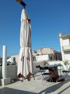 een gesloten parasol op een patio met een tafel en stoelen bij Camera Brupier in Ruvo di Puglia
