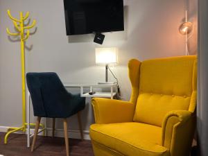 a living room with a yellow chair and a lamp at Stay Vilnius Hotel in Vilnius