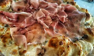 a close up of a pizza with ham on it at Cabañas Puesta del Sol in Las Peñitas