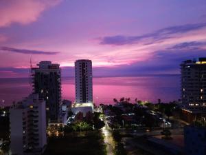 Apartamentos Salguero Suites - Cerca al Mar by SOHO في سانتا مارتا: أفق المدينة في الليل مع المحيط والمباني