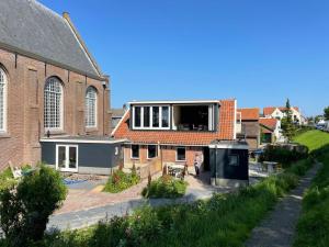 um edifício de tijolos com uma grande janela em cima em De Nieuwe Poort Kortgene em Kortgene