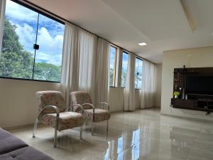 a living room with two chairs and a flat screen tv at HOTEL E RESTAURANTE NA CHÁCARA in Dourados