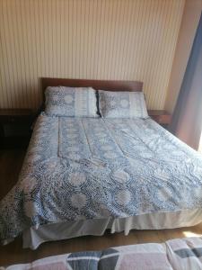 Cama con manta y almohadas azules y blancas en herencia de pioneros, en Coyhaique