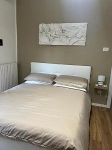 a white bed with two pillows and a painting on the wall at Vicstreet Metastasio in Naples