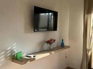 a television on a wall with a vase of flowers on a shelf at Vicstreet Metastasio in Naples +5 photos