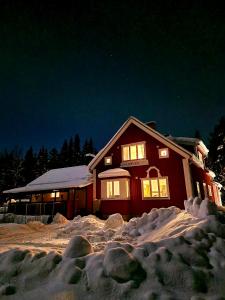 a house with lights on in the snow at night at Stationshuset Dalarna Apartments in Sörsjön