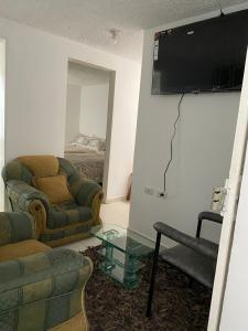 uma sala de estar com um sofá e uma televisão na parede em Acogedor Apartamento Pequeño e Independiente em Bogotá