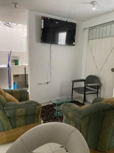 sala de estar con 2 sofás y TV en la pared en Acogedor Apartamento Pequeño e Independiente, en Bogotá