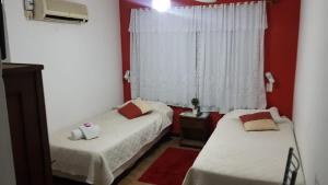 2 łóżka w pokoju z czerwonymi ścianami i oknem w obiekcie Hotel Bella Unión w mieście Bella Unión