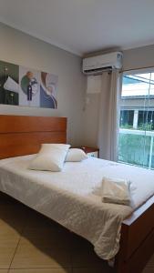 a bedroom with a large bed with white sheets and a window at Apart Angra dos Reis I in Angra dos Reis