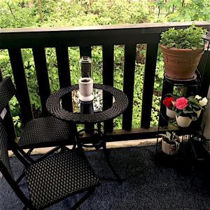 a table and a chair on a balcony with flowers at Cozy bedroom in well equipped apartment in Leatherhead