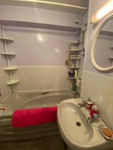 uma casa de banho com um lavatório e uma banheira com uma toalha vermelha em Cozy bedroom in well equipped apartment em Leatherhead
