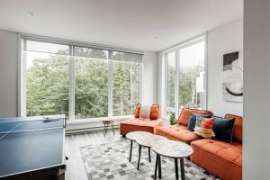 ein Wohnzimmer mit orangefarbenen Möbeln und großen Fenstern in der Unterkunft Modern Contemporary Luxury Chalet in La Conception