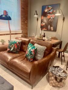 a brown leather couch with pillows in a living room at The Fifth Quarters, Grade II Listed Apartment, The Lace Market, NG1, City Centre, Nottingham, Sleeps 4 in Nottingham