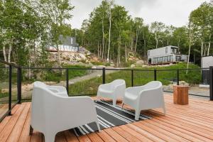 een terras met witte stoelen en uitzicht op een huis bij Modern Luxurious Chalet near Tremblant in La Conception